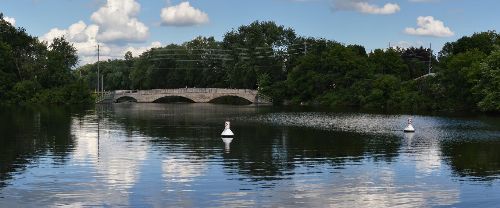 The Speed River on a summer day, with a stone bridge in the distance